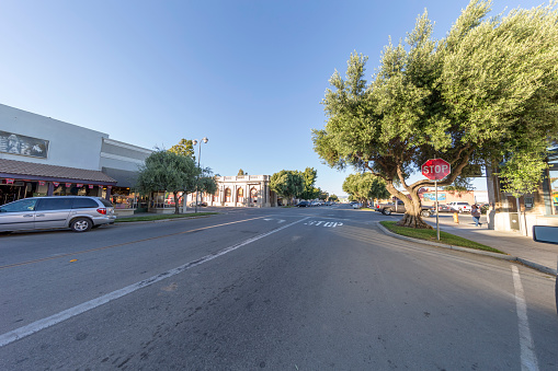 King City, California - July 8, 2016: King city downtown. Business area, stores and restraurant on the sides. Cars are parked on the street. Incidental people on the background.