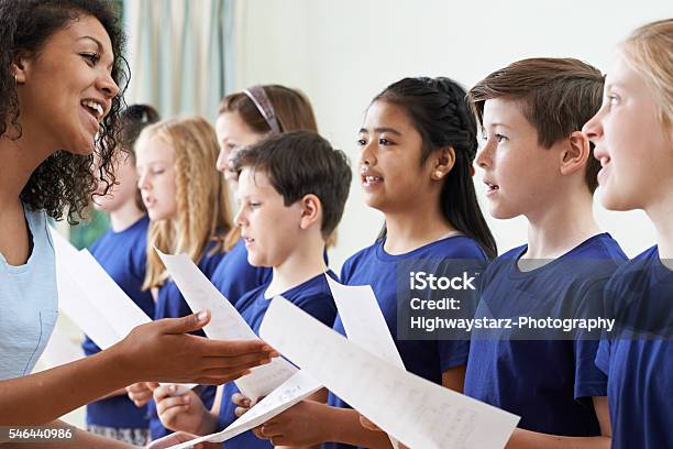 Grupo De Los Niños En Edad Escolar Con Profesor Canta En Coro Foto de stock y más banco de imágenes de Niño