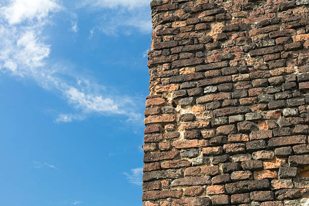 Looking up at giant new red brick wall with cloudy blue sky
