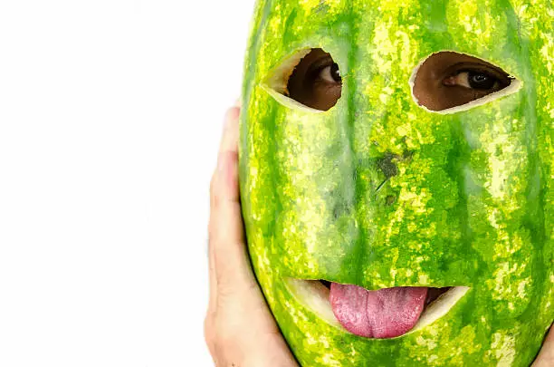 Photo of man holding mask of fruit or watermelon over his face