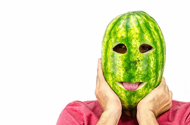 Photo of man holding mask of fruit or watermelon over his face