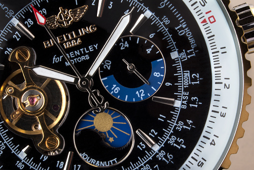 York, United Kingdom - April 27, 2013: Close-up of an expensive Swiss made Breitling chronograph wristwatch. A chronograph is a specific type of watch that is used as a stopwatch combined with a display watch. A basic chronograph has an independent sweep second hand; it can be started, stopped, and returned to zero by successive pressure on the stem. Less simple chronographs use additional complications and can have multiple independent hands to measure seconds, minutes, hours and even tenths of a second. In addition, many modern chronographs use moveable bezels as tachymeters for rapid calculations of speed or distance. Louis Moinet invented the chronograph in 1816 for use in tracking astronomical objects.