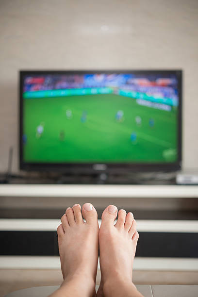 istock man laying down on a sofa  watching soccer match 546447840