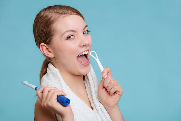 Girl with brush and tongue cleaner. Pretty young girl with electric brush and tongue cleaner. Happy woman cleaning her oral cavity caring about dental health. human mouth stock pictures, royalty-free photos & images