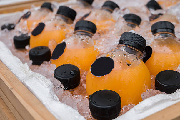 istock Orange juice bottle cooling in ice cubes for sale. 546455498