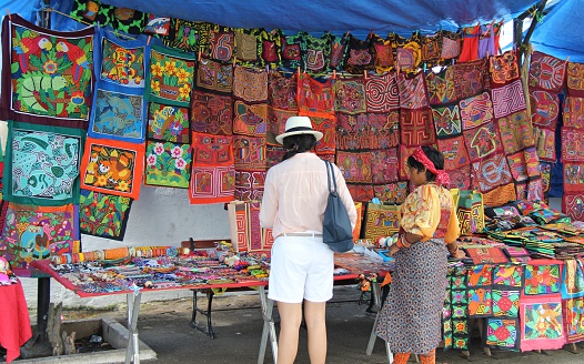 Casco Viejo, Panama - December 15, 2014: A woman is selling her Indigenous art in a local outdoor market while a tourist is browsing for souvenirs 