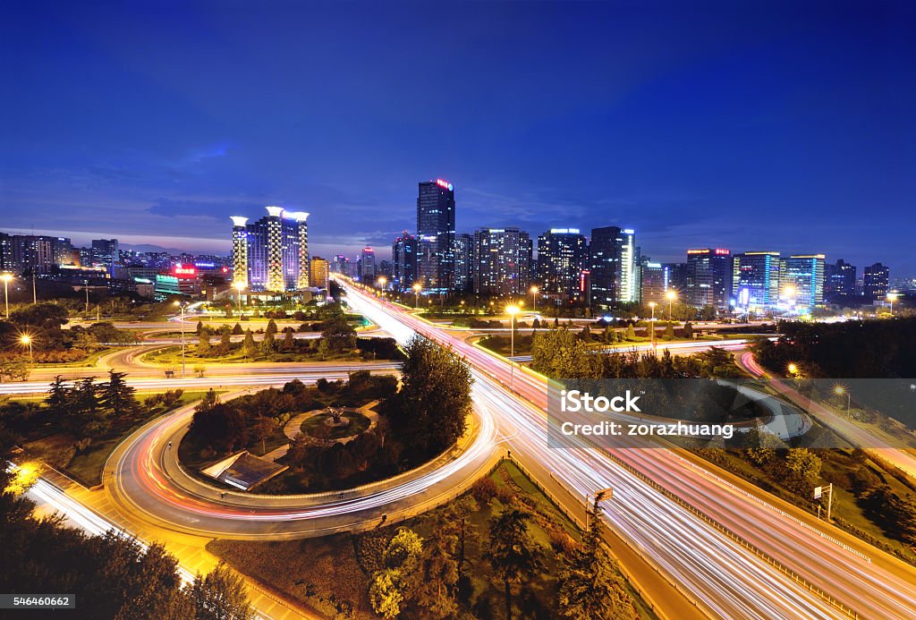 Modern Viaduct and Overpass Light trails in the modern three-dimensional ellipse viaduct and elevated road at night, Beijing. Aerial View Stock Photo