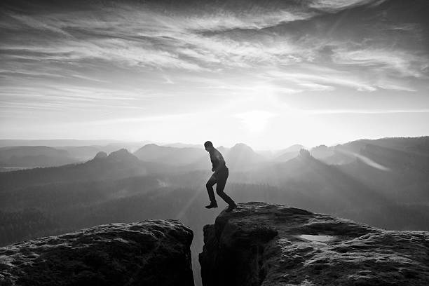 istock Man in black jumping between peaks. Dreamy daybreak 546461234