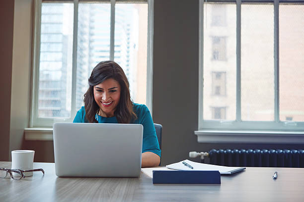 Reading the monthly employee e-newsletter Shot of a businesswoman using a laptop in an office newsletter stock pictures, royalty-free photos & images