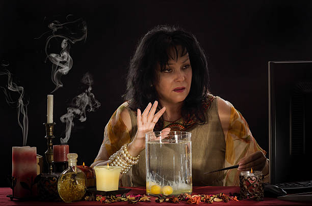 Psychic reading a shapes of egg whites Fortune teller reading of the shapes that a separated egg whites form when dropped into water. Black haired mature woman works online in front of a monitor oracular stock pictures, royalty-free photos & images