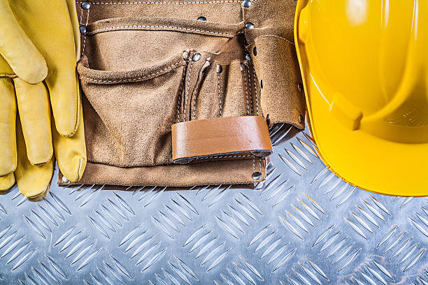 istock Leather building belt protective gloves hard hat on grooved meta 546762526