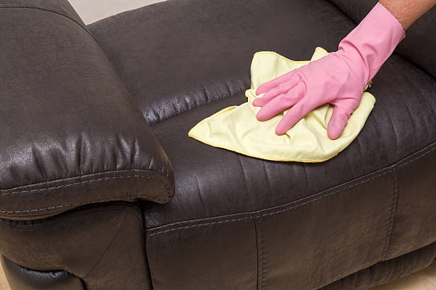 istock Hand in protective glove wiping natural leather sofa with cloth. 546762738