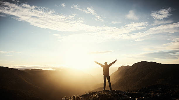 Make your own trail Shot of a young man embracing the morning sun while hiking in the mountains mountain sunrise stock pictures, royalty-free photos & images