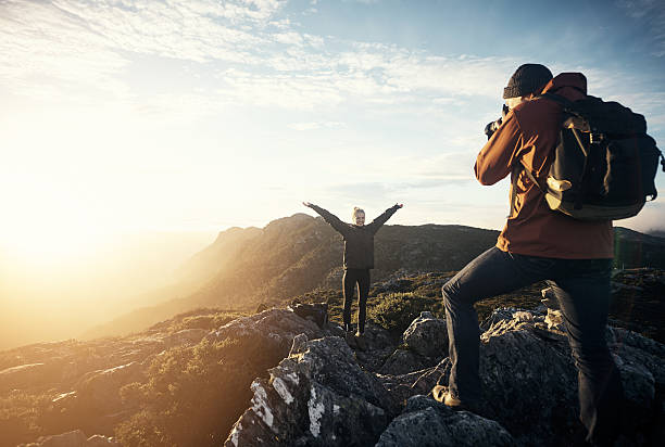 Capturing memories on the mountain Shot of a young man taking photos of his girlfriend while hiking in the mountains nature and landscapes camera stock pictures, royalty-free photos & images