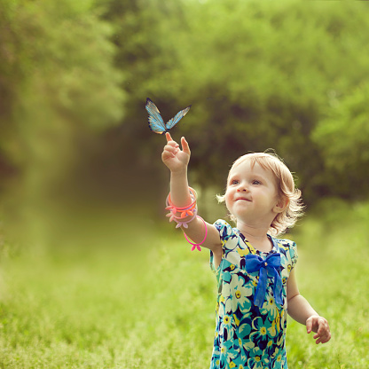 Happy girl sat on the arm of a beautiful butterfly and she enjoys communing with nature
