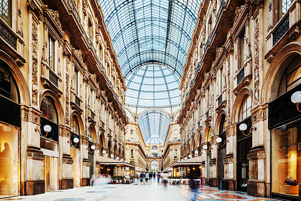 Galleria Vittorio Emanuele II in Milano, Italy Shot of the famous Galleria Vittorio Emanuele II in Milano, Italy, showing the spectacular view of an almost golden gate to luxury. Long exposure for motion blurred people rushing through. milan stock pictures, royalty-free photos & images