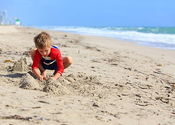 istock little boy play with sand on summer beach 546768008