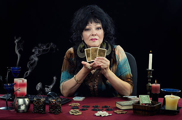 Mature clairvoyant holds three fortune telling cards stock photo
