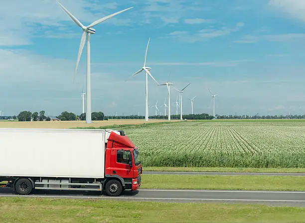 Photo of flat netherland  with truck, wind turbines and blooming crop