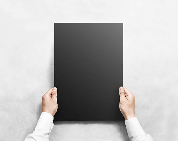 istock Hand holding black blank poster mockup, isolated. 546771510