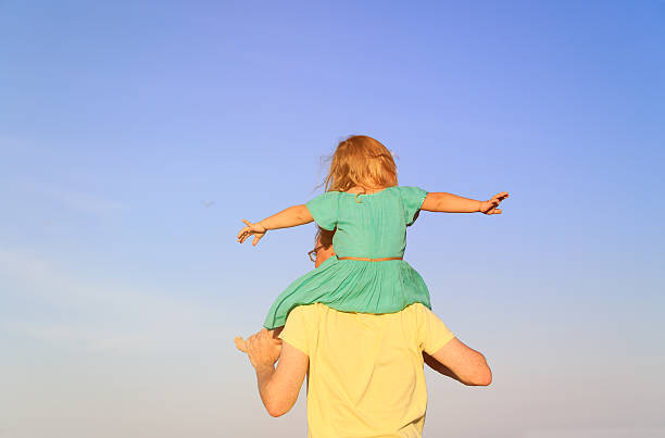 istock father and little daughter on shoulders play at sky 546772842
