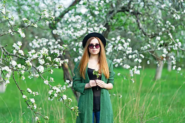 Beautiful hipster girl in spring apple garden