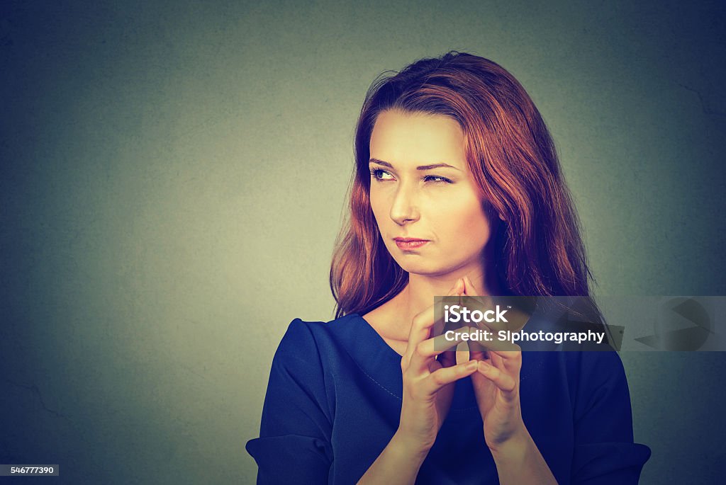 sneaky, sly, scheming young woman plotting something Closeup portrait of sneaky, sly, scheming young woman plotting something isolated on gray background. Negative human emotions, facial expressions, feelings, attitude Envy Stock Photo