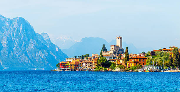 Ancient tower and colorful houses in malcesine old town Ancient tower and fortress in old town malcesine at garda lake veneto region italy high snowbound top mountains on background summer landscape with colorful houses green trees lake garda photos stock pictures, royalty-free photos & images