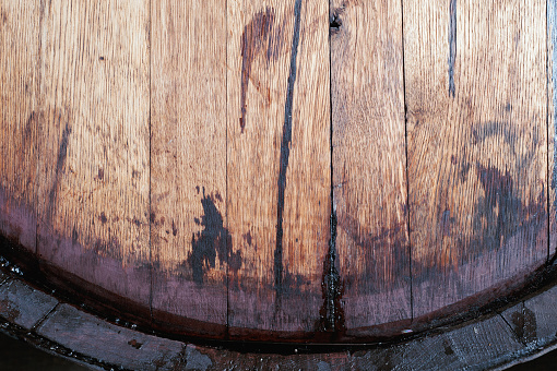 Close up of old oak wine barrel with wine drips, leak traces. Contents are leaking down the side of barrel. 