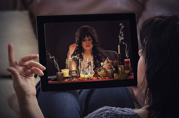 Egg divination with psychic on sofa Reclining woman on sofa communicates with aged psychic is doing egg divination online by tablet computer. Black haired fortune teller is reading a shapes of egg whites in touchscreen. oracular stock pictures, royalty-free photos & images