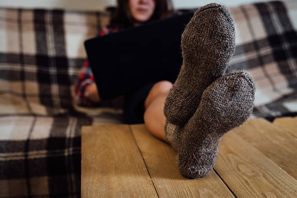 istock Young woman working with laptop on couch in knitted socks 546786140