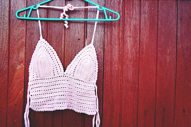 istock pink bikini crochet top halter hang on brown wood background 546788708