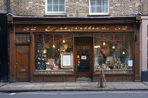 Cambridge, UK - December 23, 2015: People sit inside the well-known Fitzbillies, a traditional bakery and cafe on Trumpington Street in Cambridge, England. The shop front is decorated for the Christmas holidays.