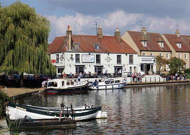 Pub At Side Of River Great Ouse, Ely, Cambridgeshire, England Ely, UK - September 20, 2015: People walk alongside the River Great Ouse and eat on the patio of a riverside pub in the small tourist town of Ely, Cambridgeshire. ely england stock pictures, royalty-free photos & images
