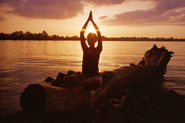 mulher fazendo yoga perto do rio - lotus root water lotus plant - fotografias e filmes do acervo