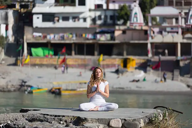 Amazing beautiful  young woman does yoga near ganges.