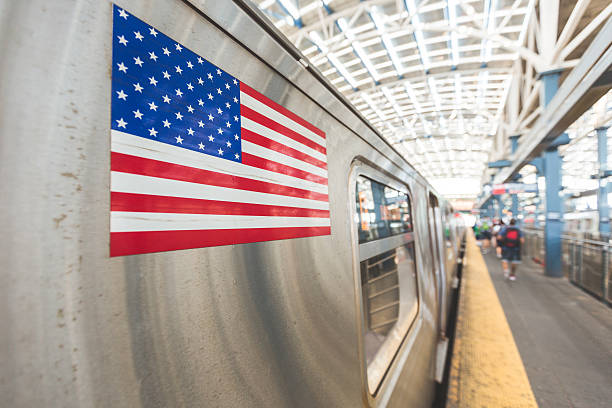 United States flag on a subway train in New York. There are some unrecognizable and blurred persons on the platform waiting to board. Transport and travel concepts. Focus on the flag