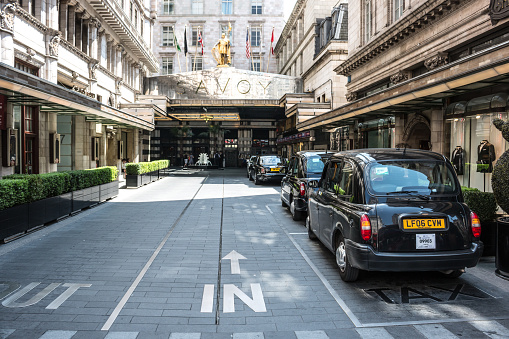 London, Westminster, United Kingdom - June 6, 2014: Luxury Hotel Savoy in London. View on main entrance and typical London Taxi cabs waiting in a queue.