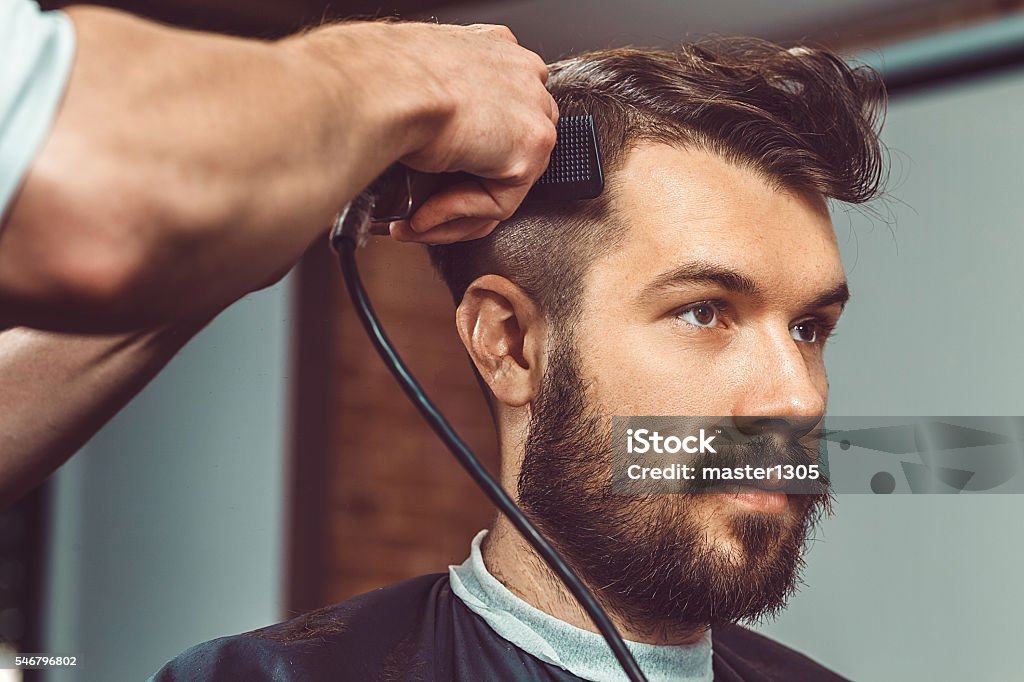 Les mains du jeune barbier faisant coupe de cheveux à l’homme attrayant - Photo de Hommes libre de droits