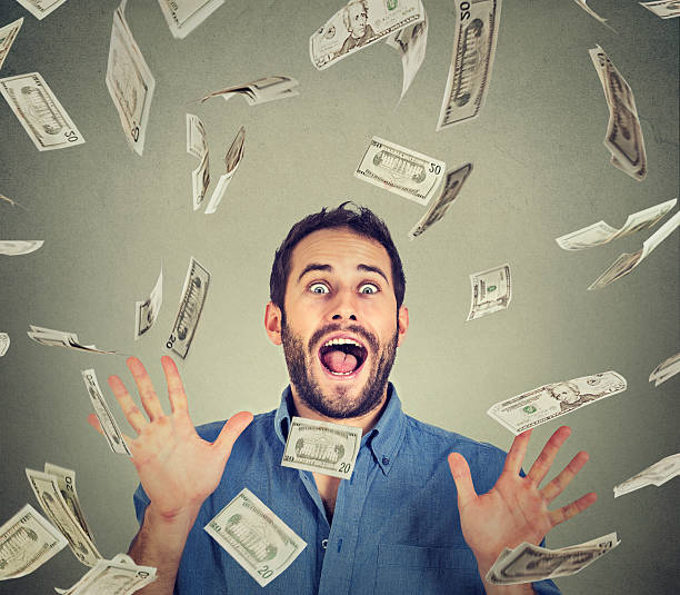 man going crazy screaming excited under money rain Happy young man going crazy screaming super excited. Portrait ecstatic guy celebrates success under money rain falling down dollar bills banknotes isolated gray background. Financial freedom concept free bingo stock pictures, royalty-free photos & images