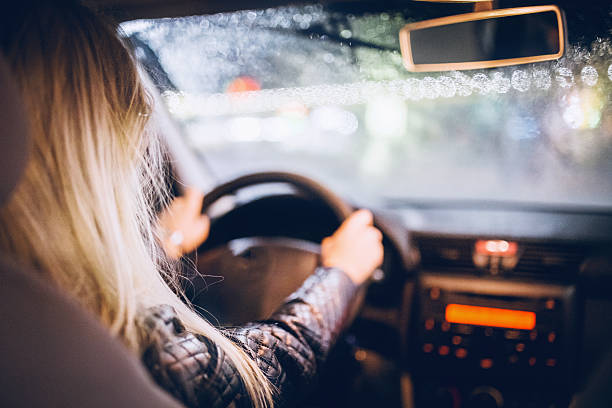 woman driving a car on rainy night - driving car drive women imagens e fotografias de stock