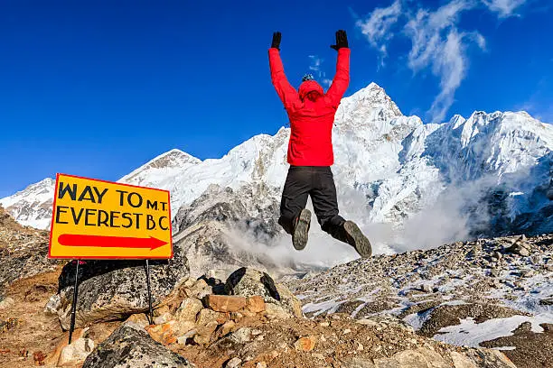 Young woman, wearing red jacket, is jumping next to the signpost "Way to Mount Everest Base Camp" in Mount Everest National Park. This is the highest national park in the world, with the entire park located above 3,000 m ( 9,700 ft). This park includes three peaks higher than 8,000 m, including Mt Everest. Therefore, most of the park area is very rugged and steep, with its terrain cut by deep rivers and glaciers. Unlike other parks in the plain areas, this park can be divided into four climate zones because of the rising altitude.http://bhphoto.pl/IS/nepal_380.jpg