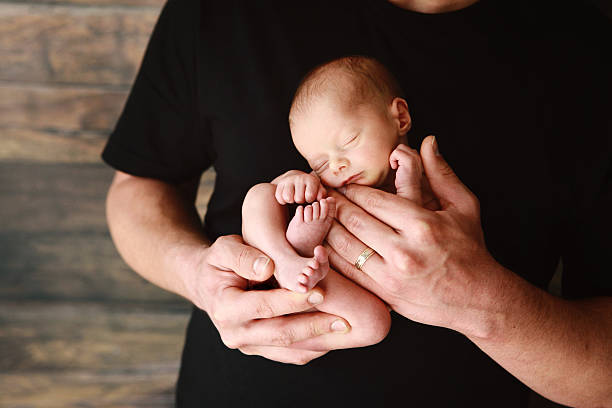 istock Newborn Baby Sleeping in Dad's Arms 546802434