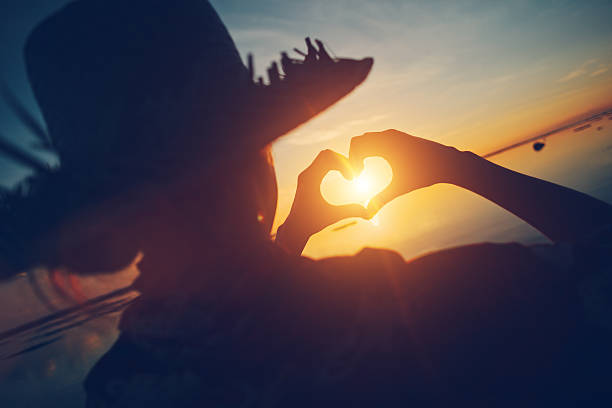 istock Woman in straw hat making heart symbol 546805382