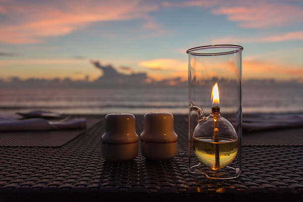 Outdoor restaurant table on the beach , wood weave table , candle light , blurred sunset background .