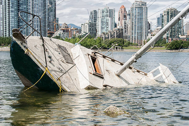 Shipwreck in front of a city Sinking sailboat abandoned on the shore of a city sunken stock pictures, royalty-free photos & images