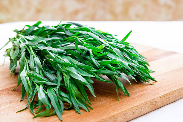 Bunch of fresh tarragon on a wooden board Bunch of fresh tarragon on a wooden board tarragon stock pictures, royalty-free photos & images