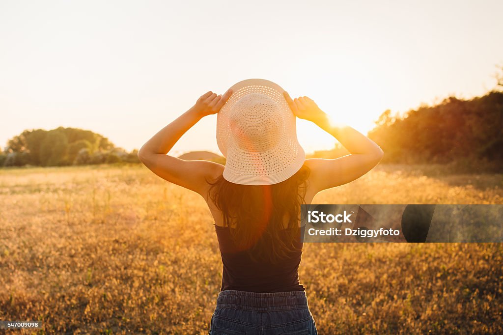 Young beautiful hippie girl celebrating summer Hippie girl in nature, holding hat looking at Sun 20-29 Years Stock Photo
