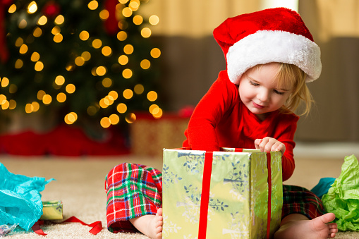 Adorable little girl opening christmas gift