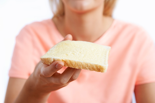 Woman Eating Slice Of White Bread With Margarine